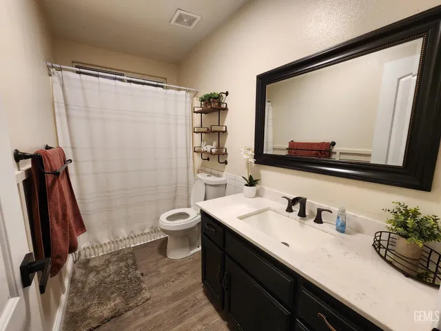 a bathroom with a granite countertop sink toilet and shower