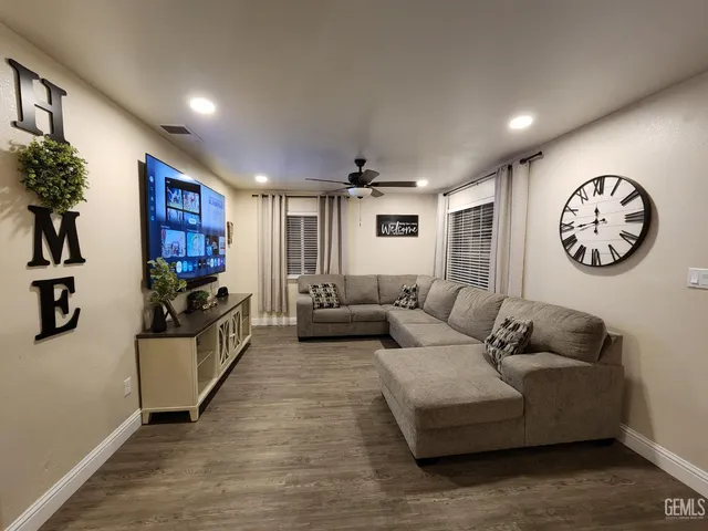 a living room with furniture a clock and a flat screen tv