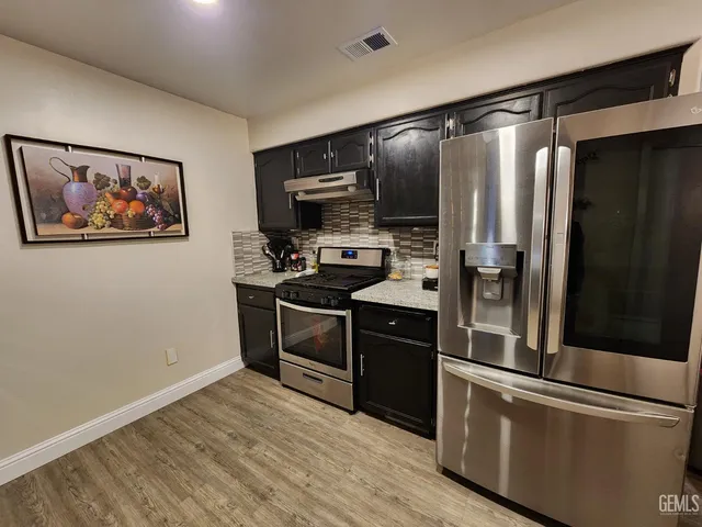 a kitchen with stainless steel appliances granite countertop a refrigerator and a stove top oven