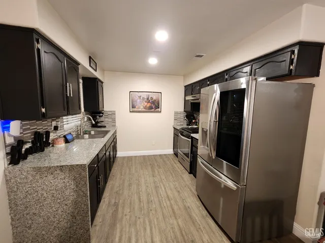 a kitchen with stainless steel appliances granite countertop a refrigerator stove and sink