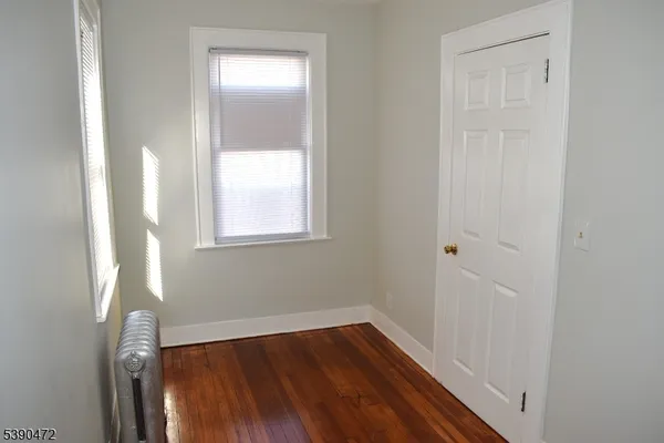 a view of a hallway with wooden floor and a window