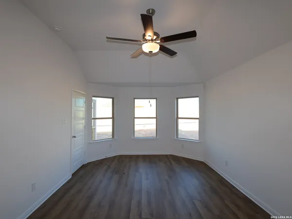 an empty room with wooden floor fan and windows