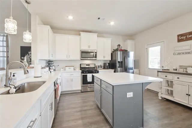 a kitchen that has a lot of white cabinets and stainless steel appliances