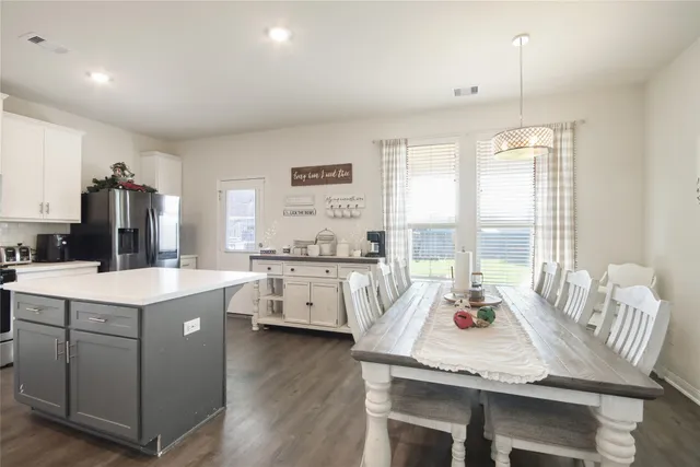 a open dining room with stainless steel appliances kitchen island a table and chairs
