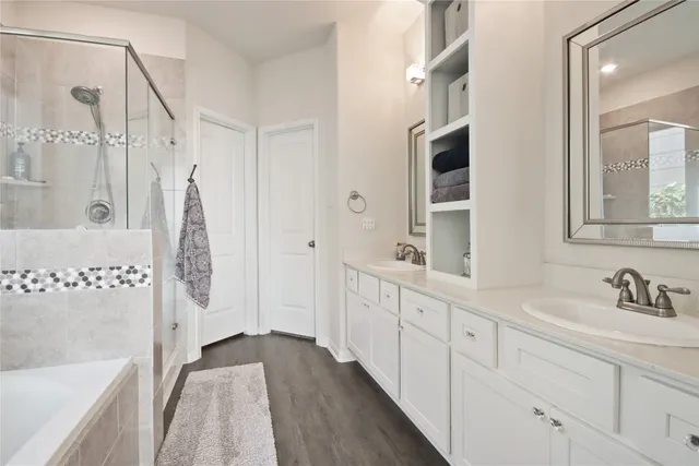 a bathroom with a double vanity sink a mirror a bathtub and shower