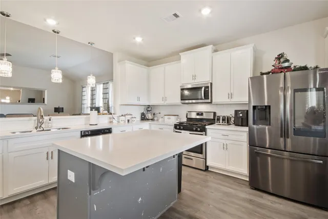 a kitchen with a sink a counter top space stainless steel appliances and cabinets