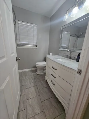 a bathroom with a granite countertop sink toilet and mirror