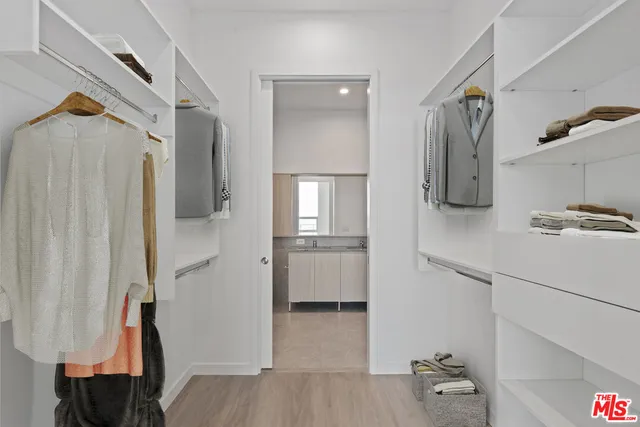 a view of walk in closet with clothes and shoes