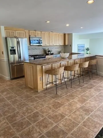 a kitchen with stainless steel appliances a refrigerator a stove a sink a dining table and chairs
