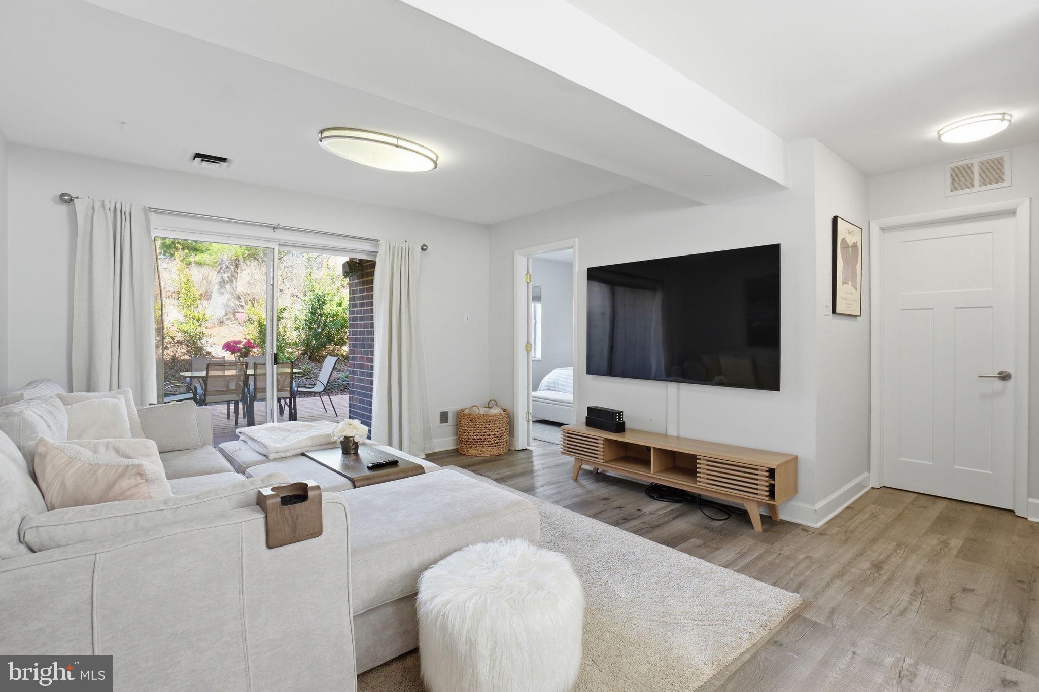 11025 Saffold Way Reston, VA 20190 - Photo 27 of 50 a living room with furniture a flat screen tv and a floor to ceiling window