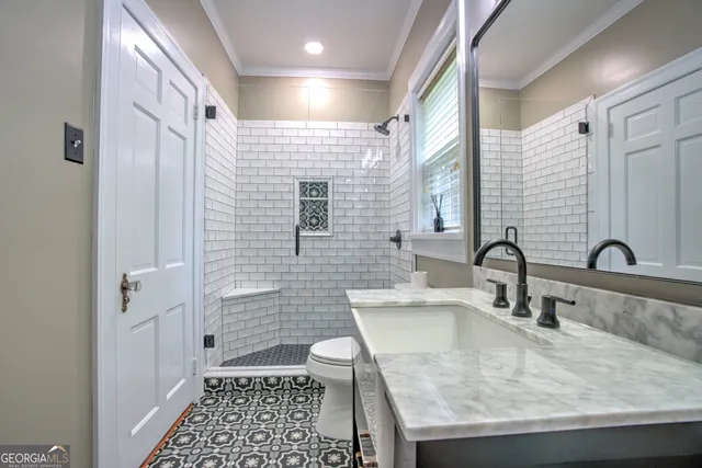 a bathroom with a granite countertop sink a toilet and shower