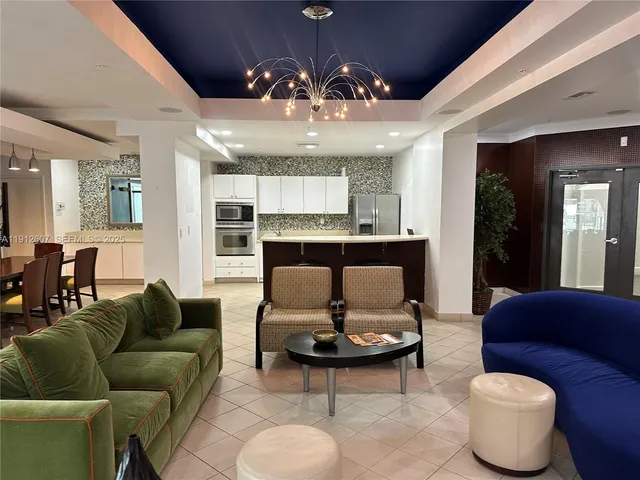 a living room with furniture kitchen view and a chandelier