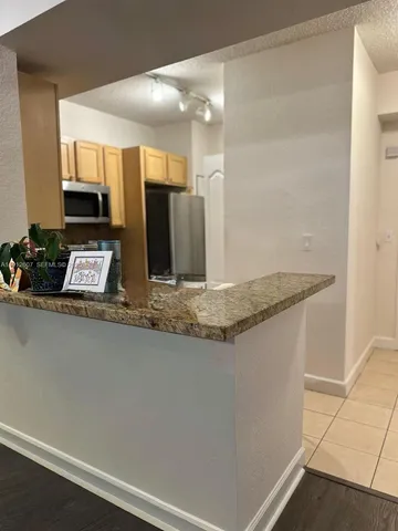 a view of a kitchen with kitchen island a sink wooden floor and living room