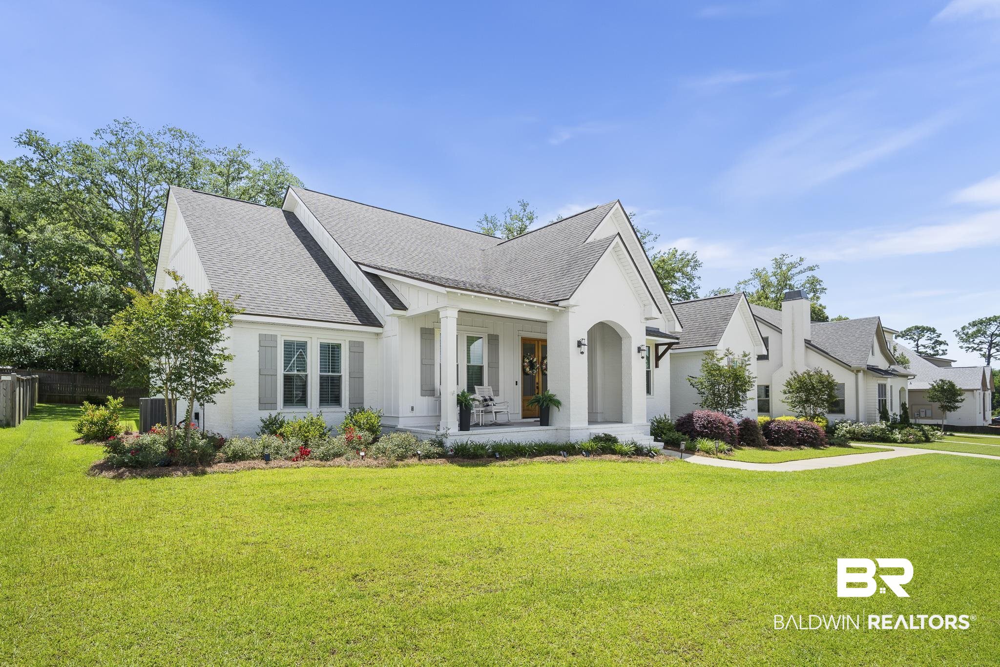 21702 Pillars Street Fairhope, AL 36532 - Photo 40 of 54 Craftsman-style home featuring white siding, a dark gray roof, a covered porch with white columns, a meticulously manicured lawn, and mature landscaping