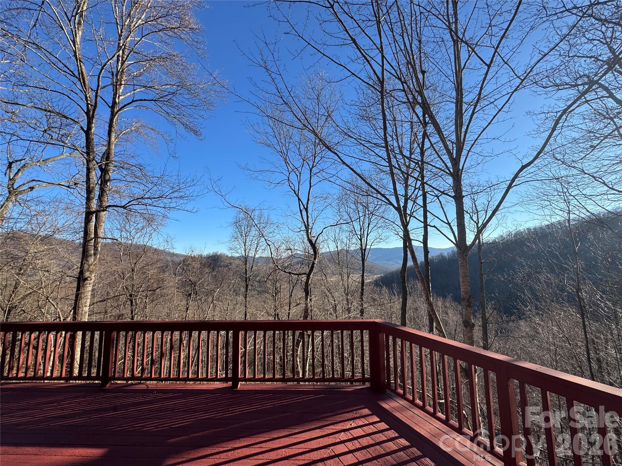 a view of deck with wooden fence and large trees