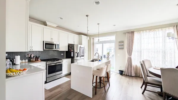 a kitchen with stainless steel appliances granite countertop a stove a refrigerator a kitchen island a dining table and chairs with wooden floor