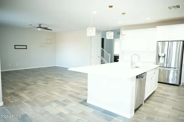 a large white kitchen with a sink a refrigerator and a stove top oven