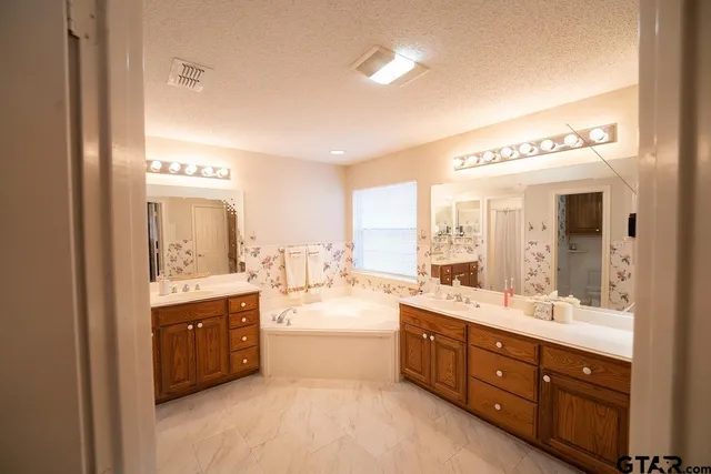 a spacious bathroom with a double vanity sink a large mirror and a bathtub