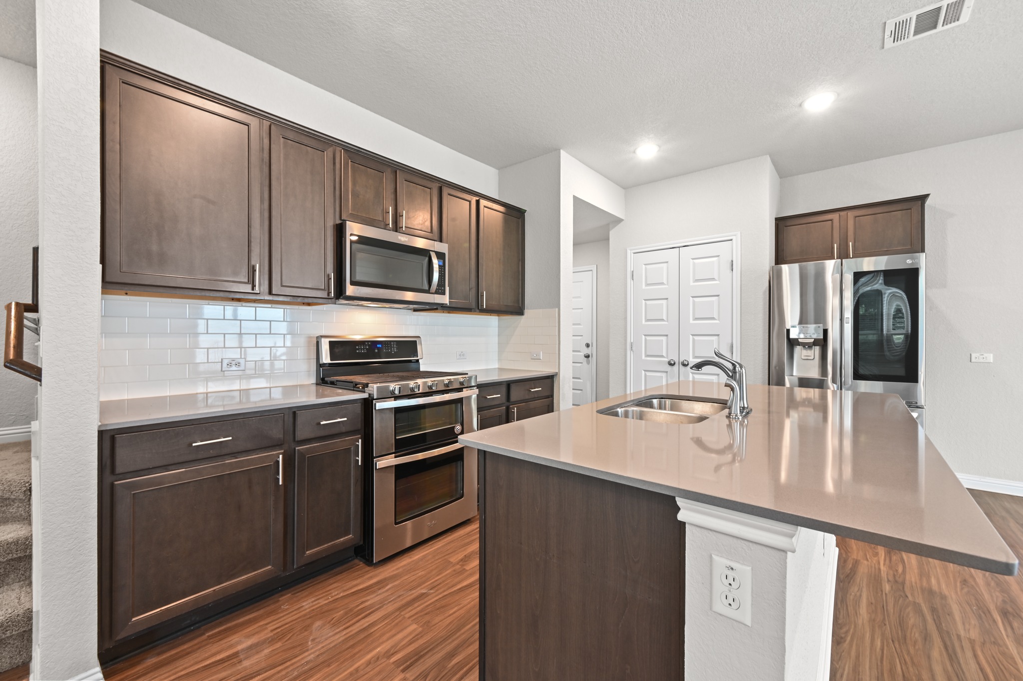 8201 Frida Bend Austin, TX 78744 - Photo 16 of 29 A contemporary kitchen showcasing rich cabinetry, sleek stainless steel appliances, and gleaming countertops with an inviting island.