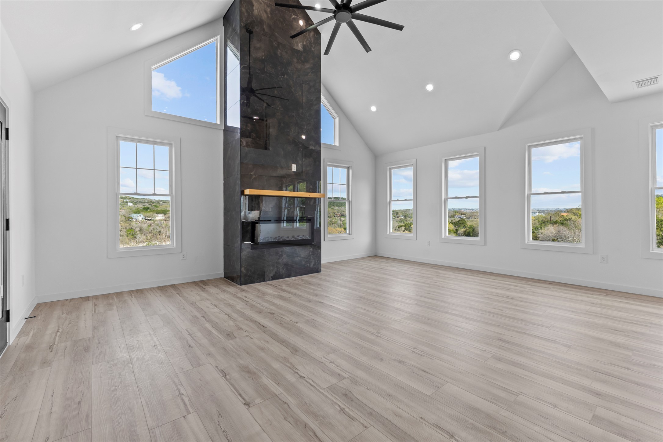 11005 Beach Road Leander, TX 78641 - Photo 22 of 40 Unfurnished living room featuring a high ceiling, a large fireplace, ceiling fan, light wood-type flooring, and recessed lighting