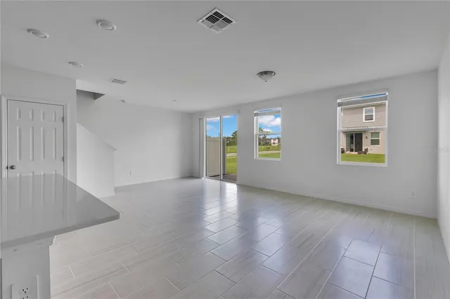 a view of an empty room with window and wooden floor