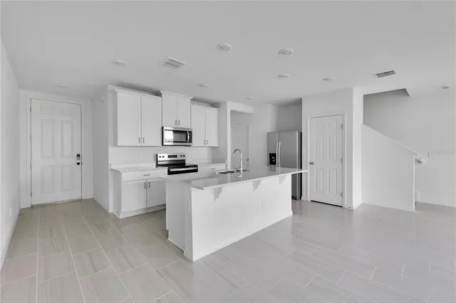 a kitchen with stainless steel appliances a refrigerator sink and white cabinets