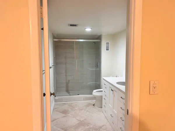 a bathroom with a granite countertop toilet a sink and a shower