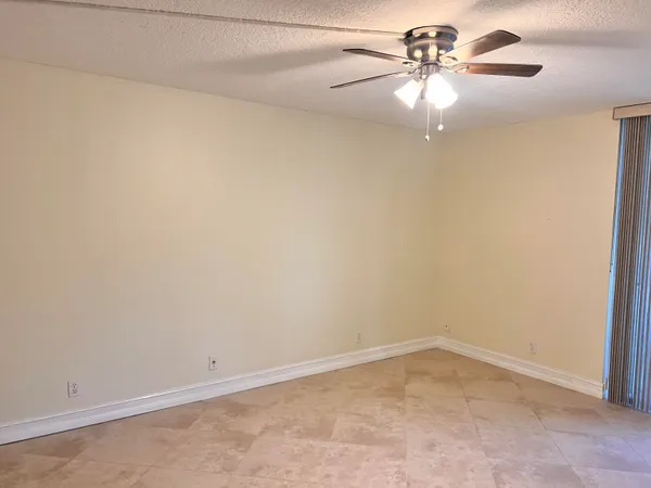 an empty room with a window and a fan