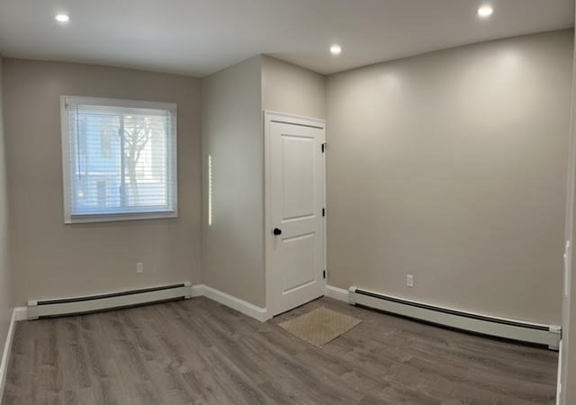 95 Cottage Street, Unit A Boston, MA 02128 - Photo 16 of 18 an empty room with wooden floor and windows