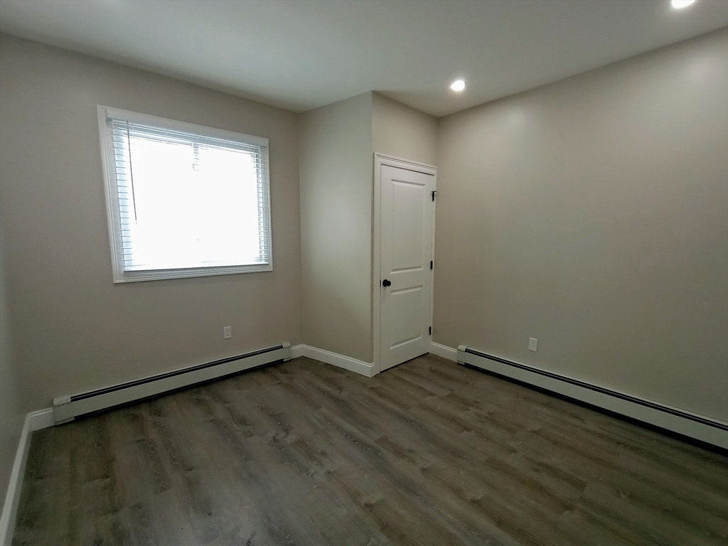 95 Cottage Street, Unit A Boston, MA 02128 - Photo 3 of 18 an empty room with wooden floor and windows