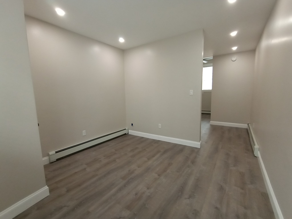 95 Cottage Street, Unit A Boston, MA 02128 - Photo 4 of 18 an empty room with wooden floor and windows
