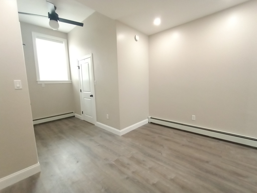 95 Cottage Street, Unit A Boston, MA 02128 - Photo 6 of 18 an empty room with wooden floor and windows