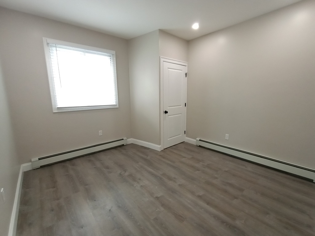95 Cottage Street, Unit A Boston, MA 02128 - Photo 7 of 18 an empty room with wooden floor and windows