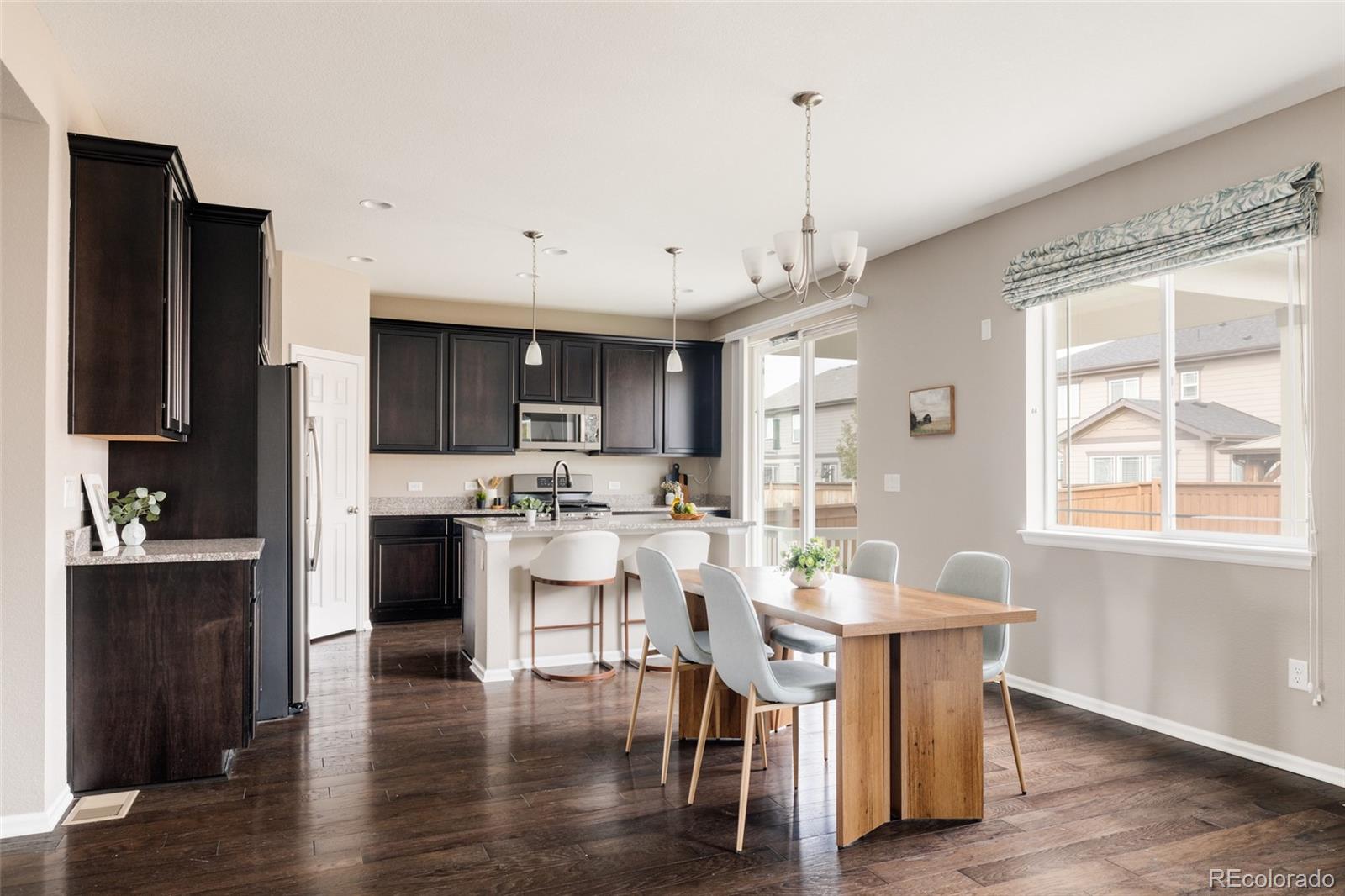 220 South Ider Way Aurora, CO 80018 - Photo 5 of 28 a kitchen with stainless steel appliances granite countertop a stove a refrigerator a kitchen island a dining table and chairs with wooden floor