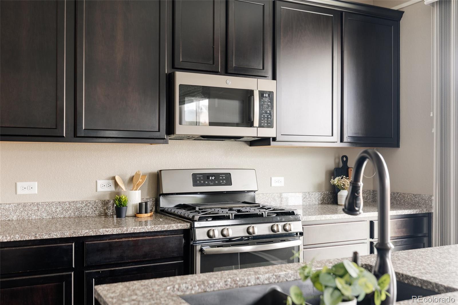 220 South Ider Way Aurora, CO 80018 - Photo 9 of 28 a kitchen with stainless steel appliances granite countertop a stove a microwave and cabinets