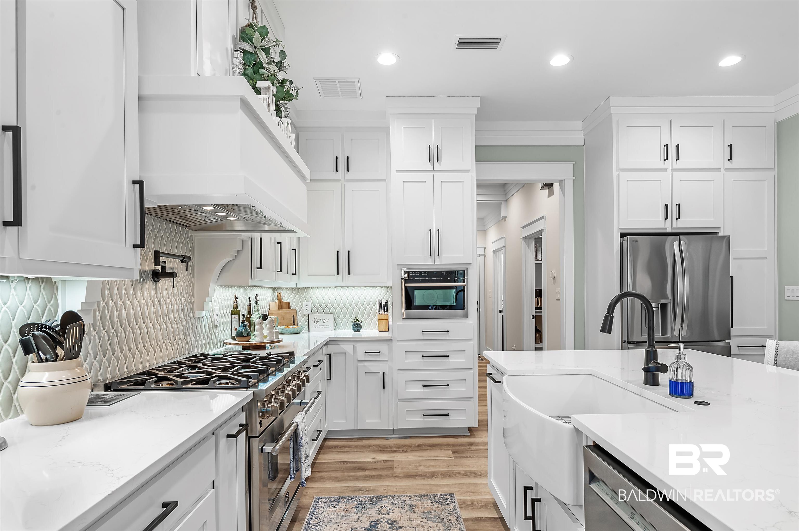 9144 Harvest Ridge Fairhope, AL 36532 - Photo 25 of 58 Kitchen featuring decorative backsplash, white cabinets, visible vents, custom exhaust hood, and stainless steel appliances