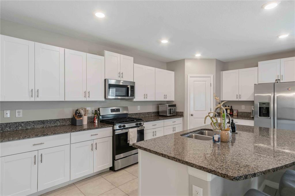 9440 Lemon Drop Loop Sun City Center, FL 33573 - Photo 11 of 55 a kitchen with stainless steel appliances granite countertop a sink a stove and a refrigerator