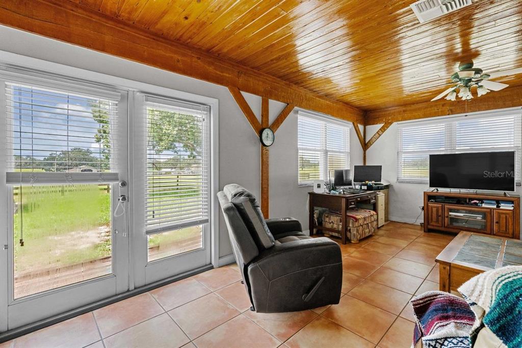 38730 Mickler Road Dade City, FL 33523 - Photo 13 of 38 a living room with furniture a flat screen tv and floor to ceiling windows