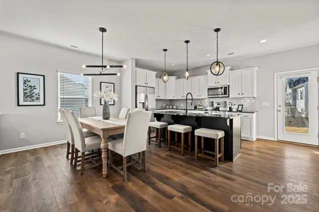 a view of a dining room and livingroom with furniture wooden floor a chandelier