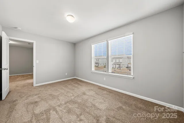 a view of an empty room with closet and a window