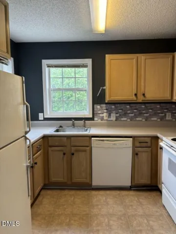 a kitchen with stainless steel appliances granite countertop a sink a stove a refrigerator a washer dryer and white cabinets
