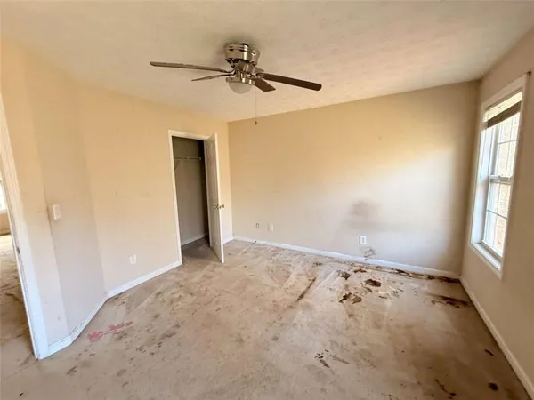 an empty room with windows and fan