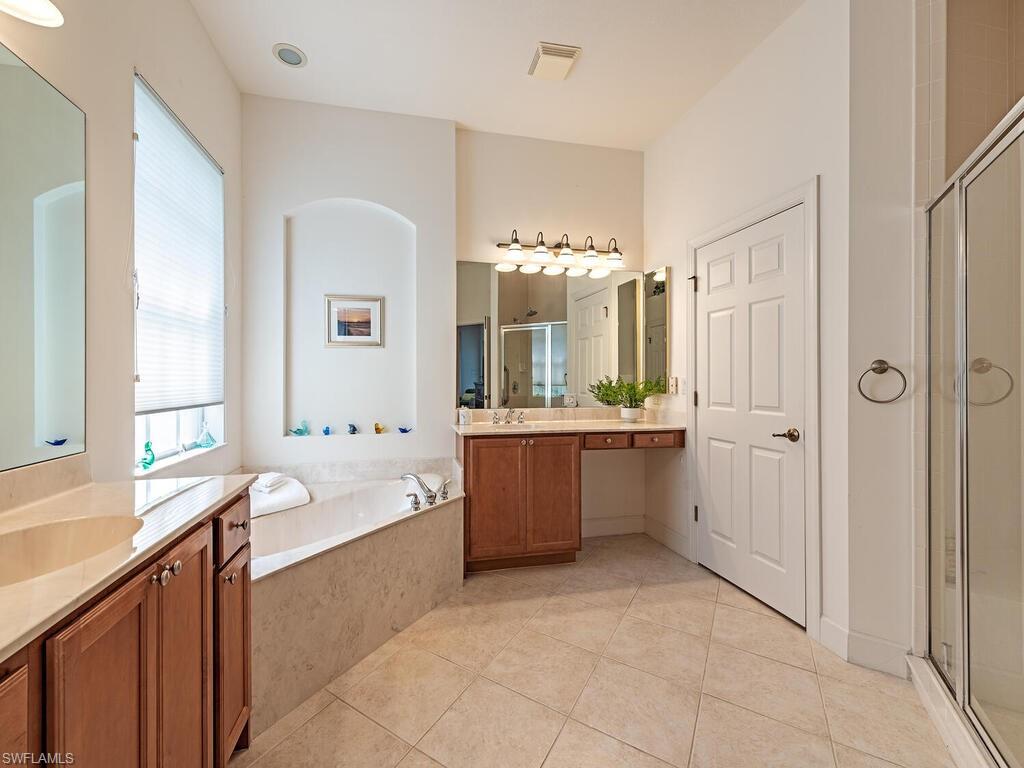 16105 Parque Lane Naples, FL 34110 - Photo 11 of 34 a bathroom with a bathtub a double vanity sink a vanity a window and a mirror