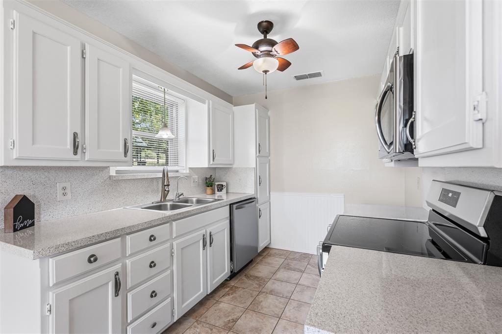 1221 East Fm 4 Cleburne, TX 76031 - Photo 15 of 35 a kitchen with a sink dishwasher and white cabinets with wooden floor