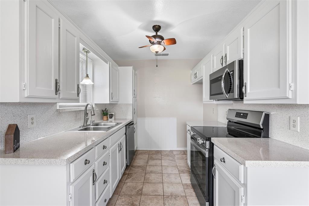 1221 East Fm 4 Cleburne, TX 76031 - Photo 17 of 35 a kitchen with stainless steel appliances granite countertop a sink stove oven and white cabinets