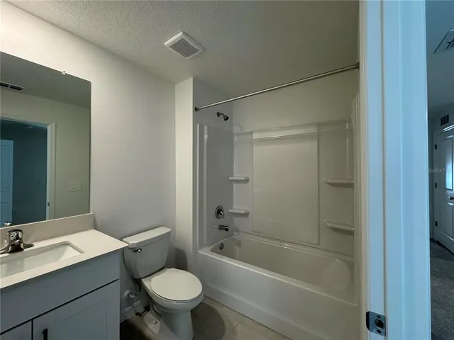 a bathroom with a bathtub shower sink vanity mirror and toilet