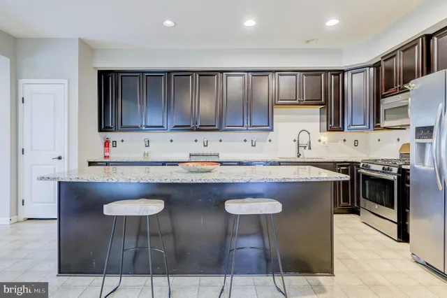 a kitchen with stainless steel appliances granite countertop a table chairs sink and cabinets