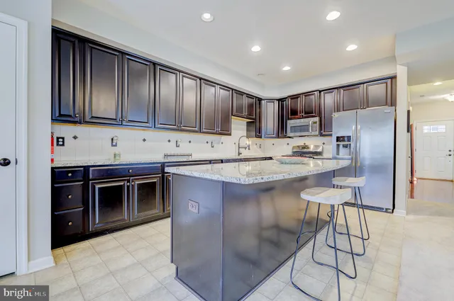 a kitchen with kitchen island granite countertop a stove a sink and a refrigerator