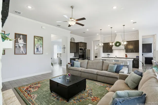 a living room with furniture kitchen view and a chandelier