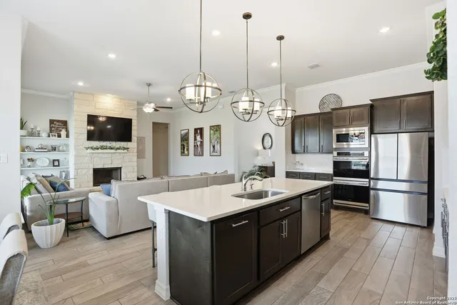 a open kitchen with stainless steel appliances granite countertop a stove kitchen island a refrigerator and a fireplace with wooden floor